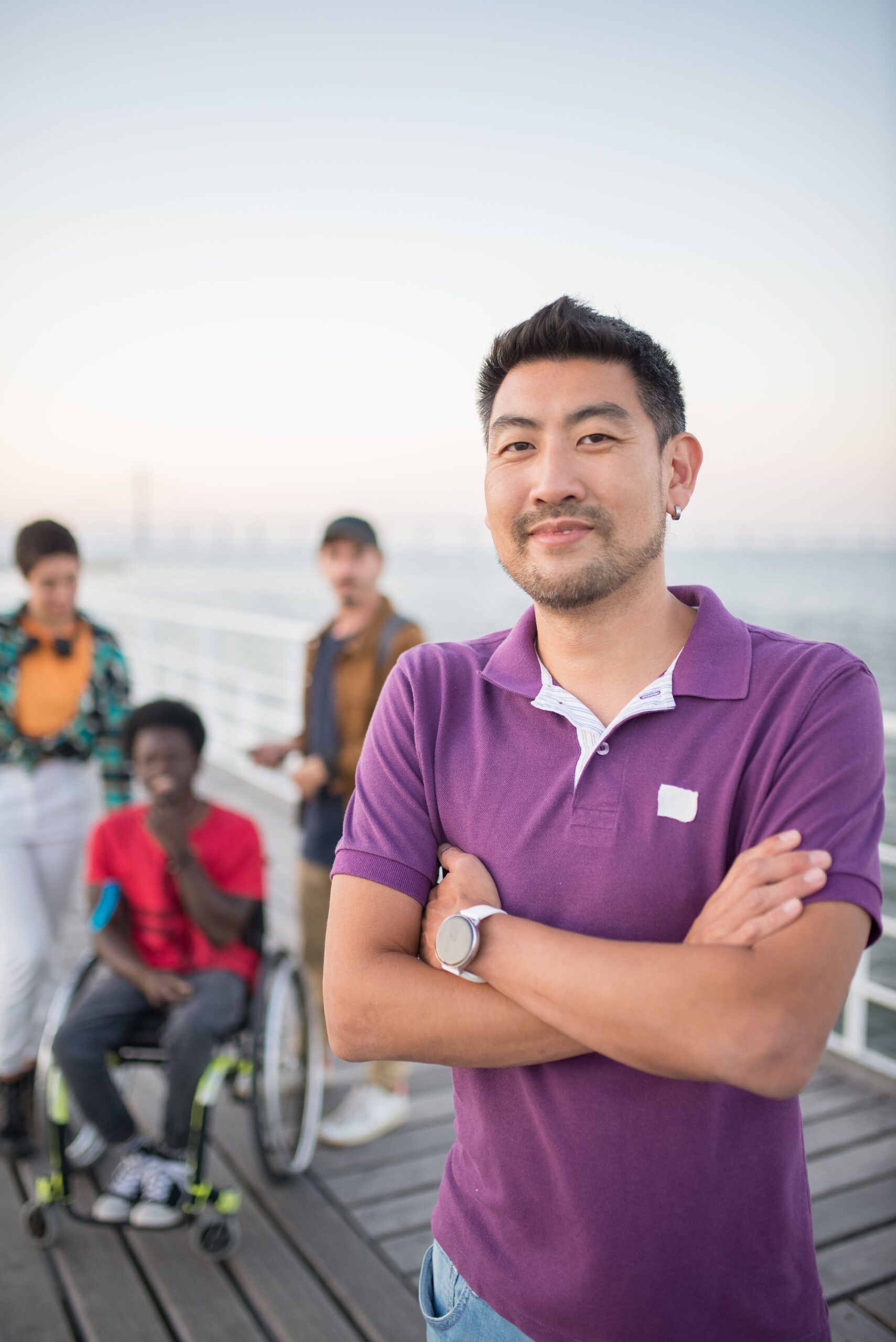Smiling man in purple shirt with friends on a pier in Portugal.